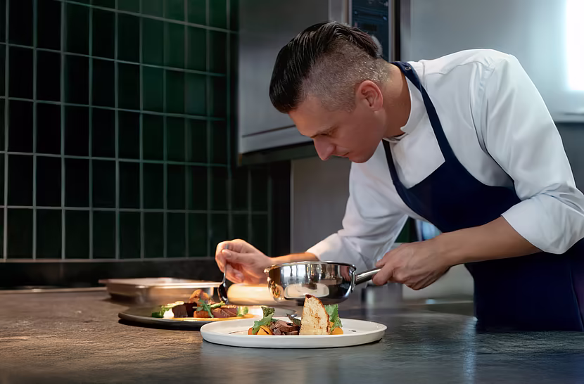 Koch richtet die Speisen in der Küche an