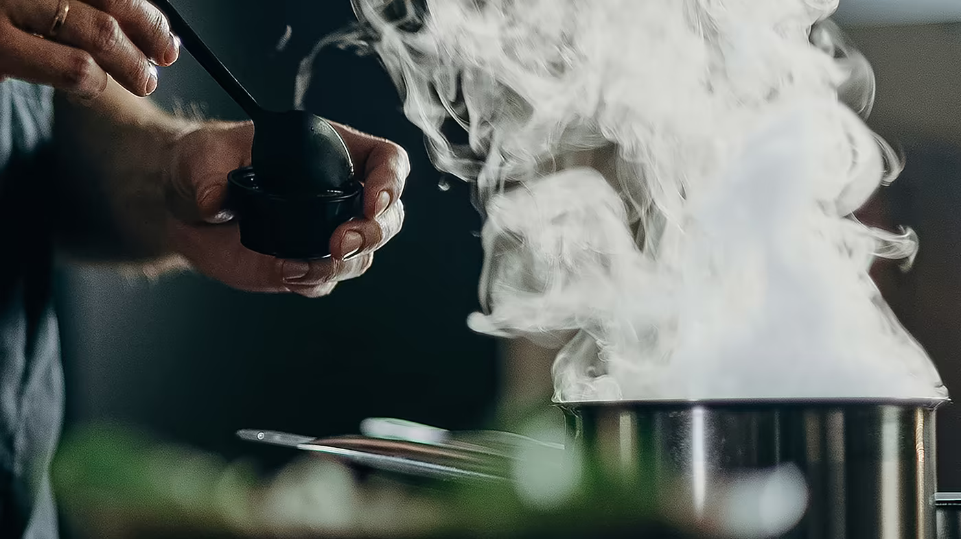 Koch würzt ein Gericht während des Kochvorgangs in der Hotelküche.