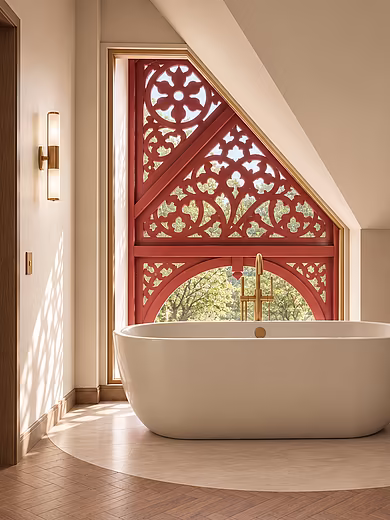 Freistehende Badewanne in der Signature Suite im Art-Déco-Stil vor dem historischen Giebelfenster mit Blick auf den Achensee