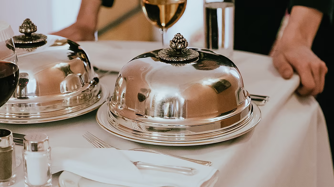 Servicemitarbeiter serviert Speisen am gedeckten Tisch im Restaurant.