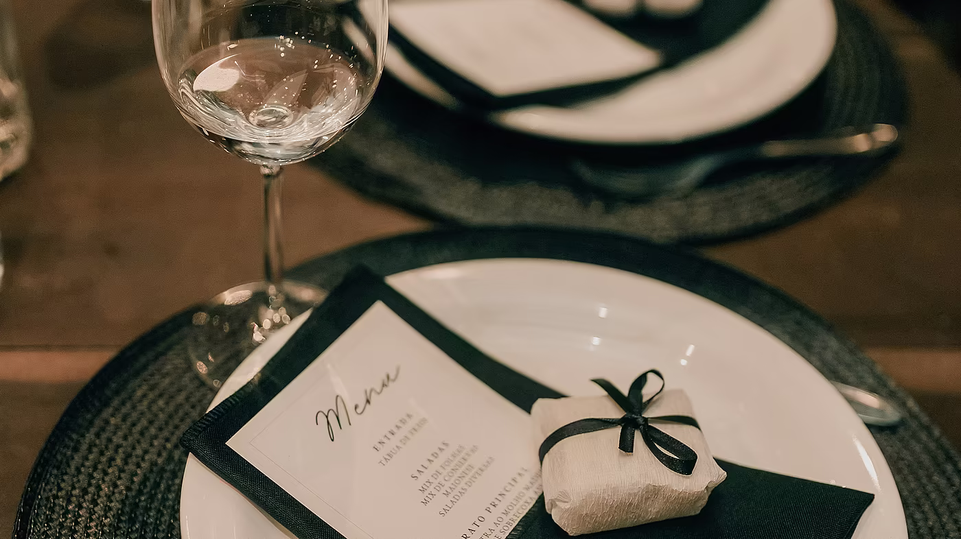 Gedeckter Tisch im Restaurant mit Menükarte, Serviette und Weinglas.