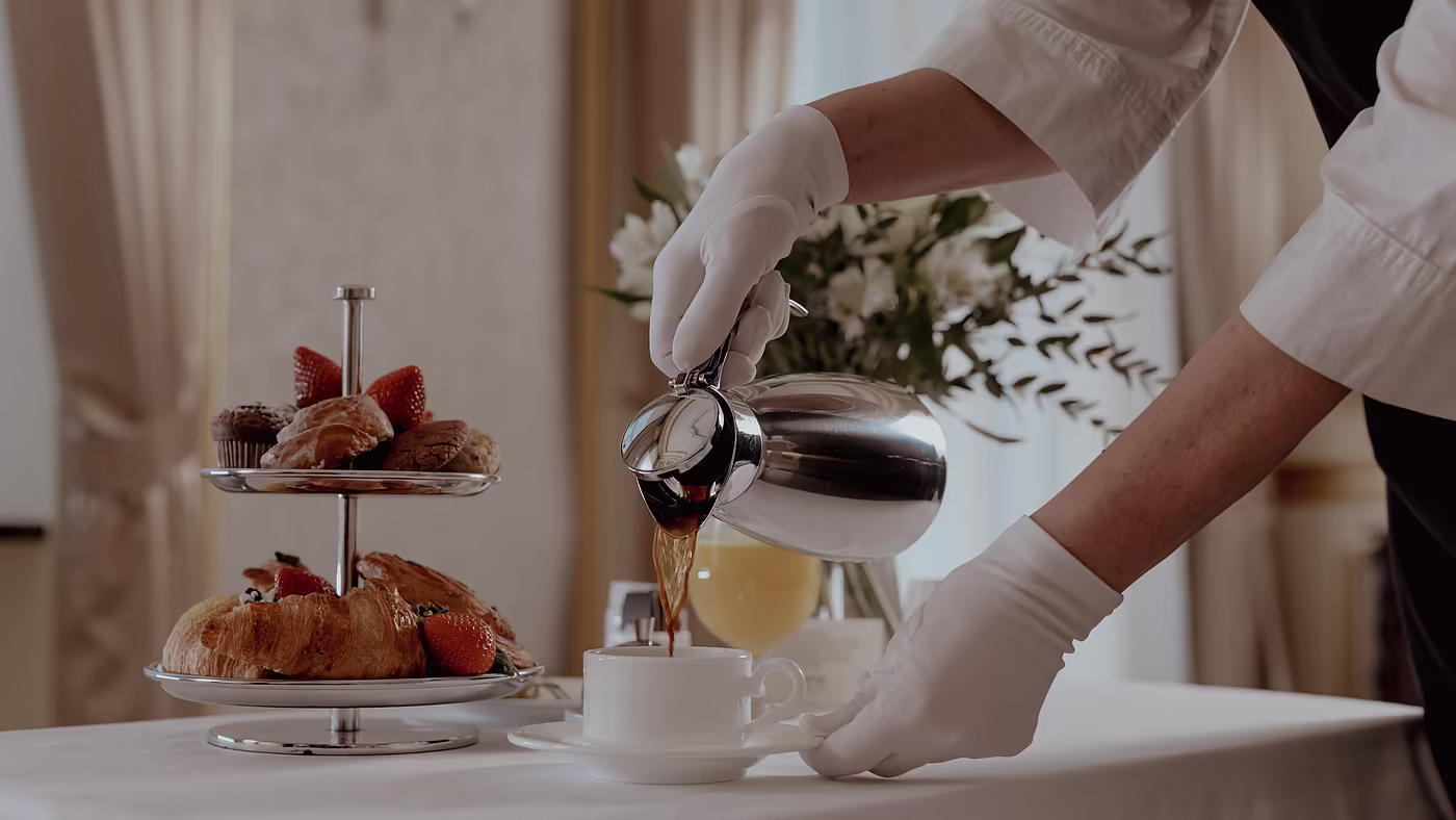 Mitarbeiter serviert Kaffee und Frühstück am Tisch im Hotel.